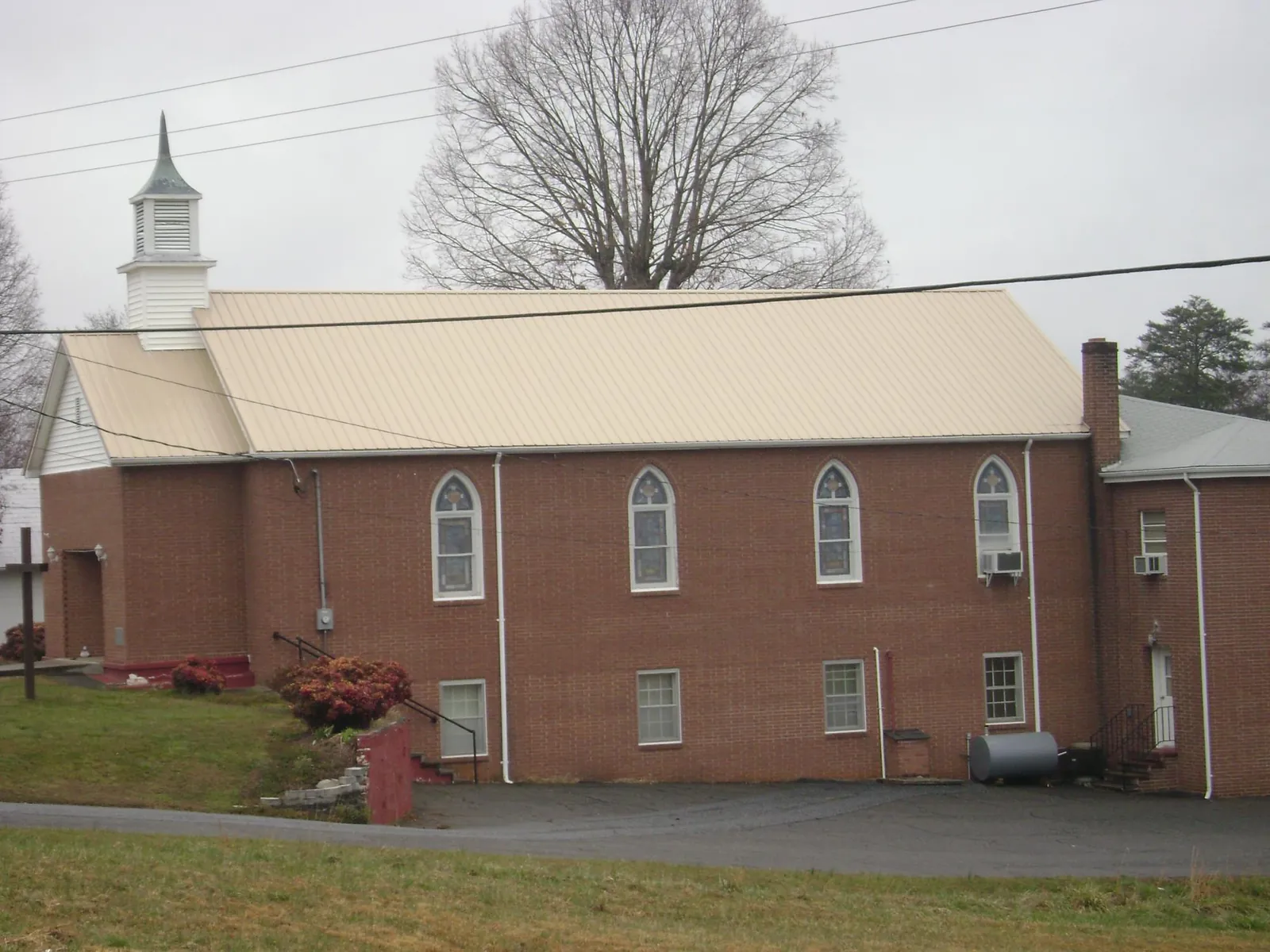 New tan metal roof on a brick church with a white steeple in Hamburg