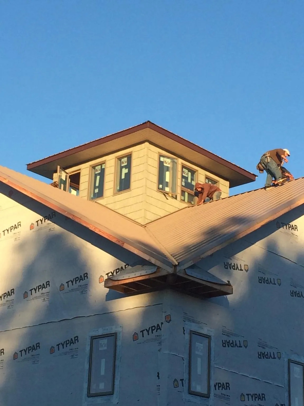 Roofers working around a rooftop cupola on a new metal roof at sunset — Roof Waterproofing in Hamburg by Roofing Brothers